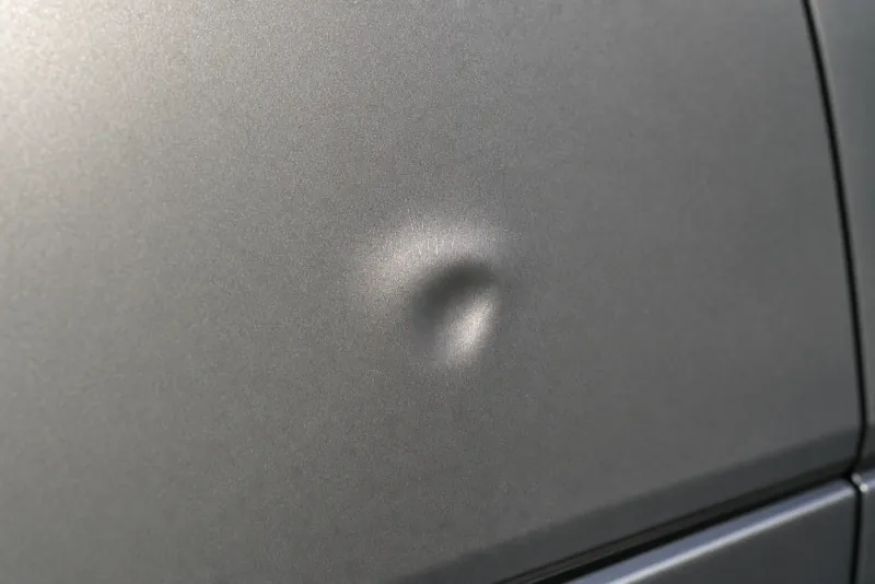 Close-up photograph of prior damage on a car panel