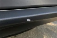 Close-up of a paint chip on the rear bumper edge